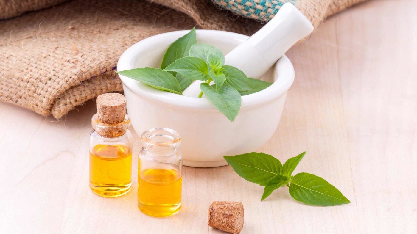 Aromatherapy essential oils in bottles next to a mortar